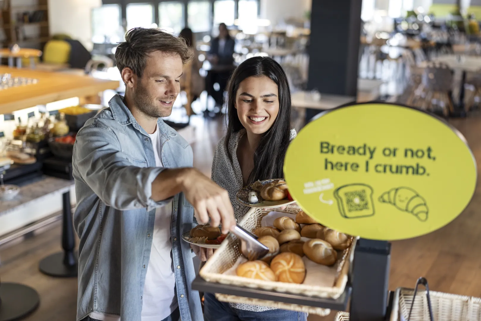 Guests choosing rolls at the hotel breakfast buffet.