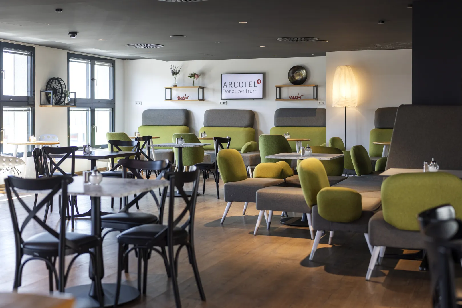 Modern hotel café with green and gray furniture, stylishly arranged.