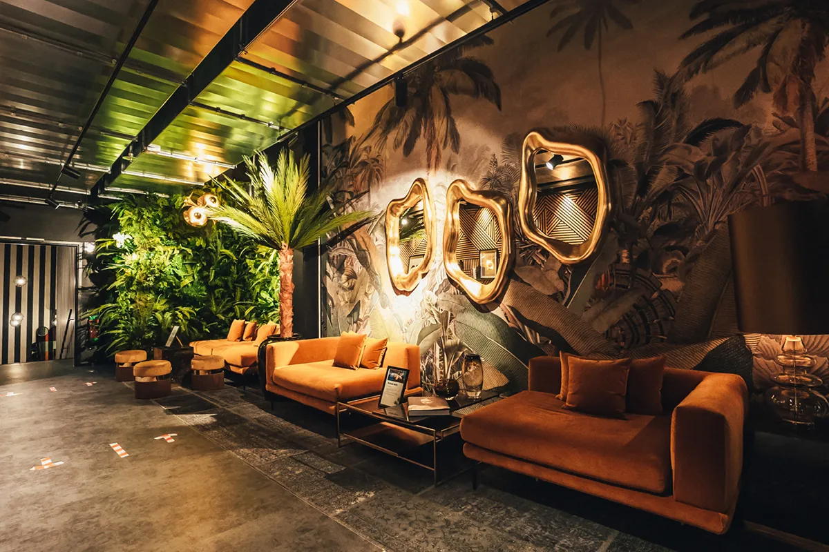 Modern gym with a green wall, stylish orange sofas, and artistically designed mirrors.
