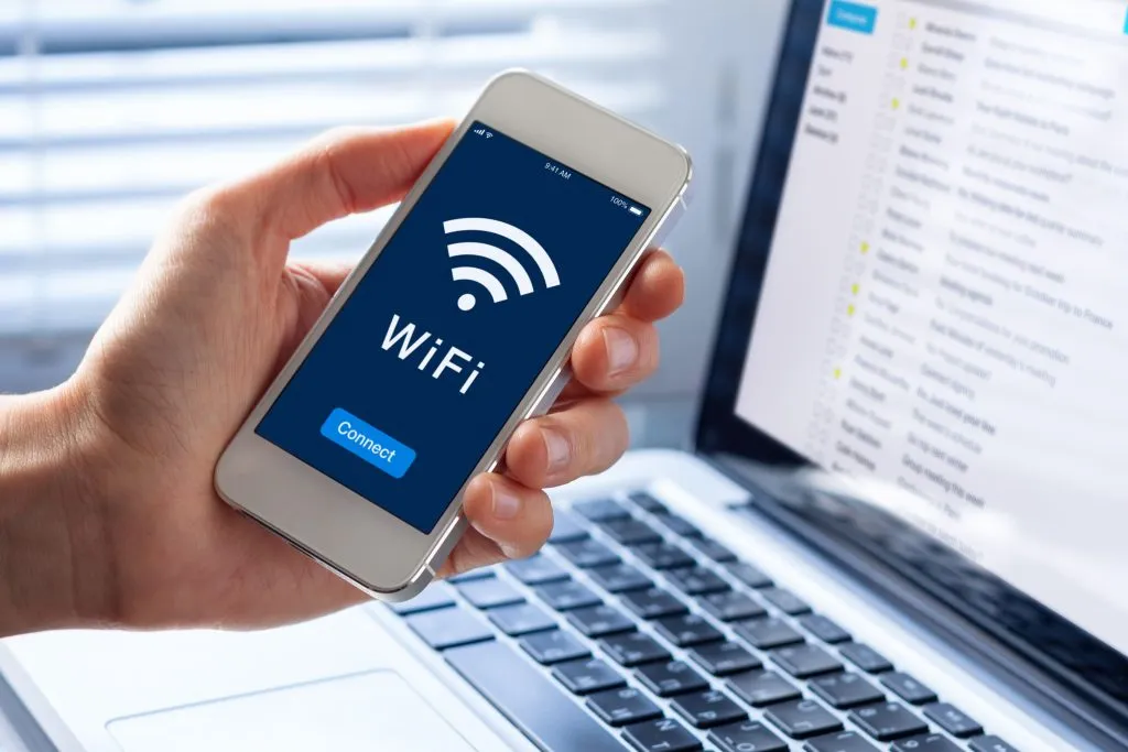 Smartphone zeigt WiFi-Verbindung neben Laptop an.